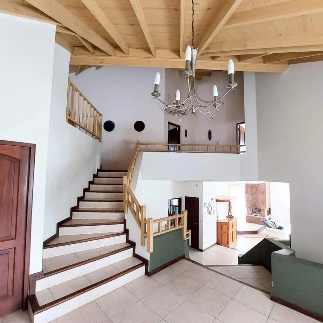 Escalera interior de doble altura con vigas de madera a la vista